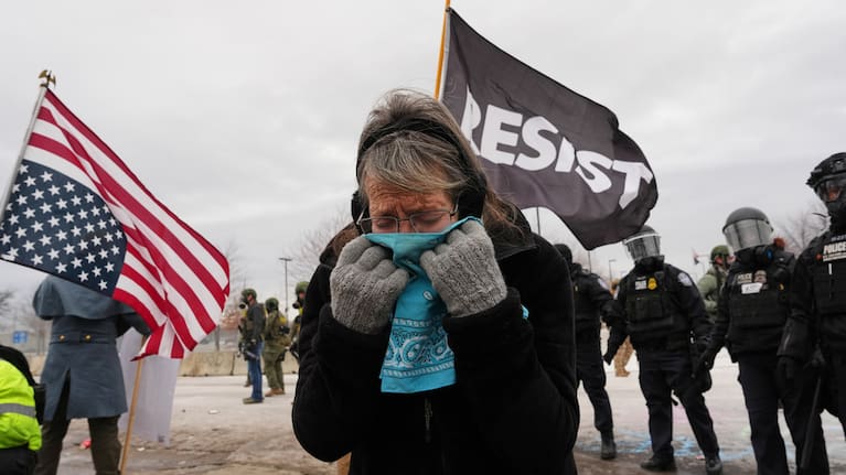 A woman covers her face from tear gas as federal immigration officers confront protesters outside Bishop Henry Whipple Federal Building, Thursday, January 15, 2026, in Minneapolis.