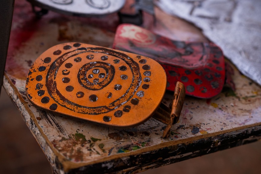 Two pieces of brightly coloured metal with symbols painted on them.