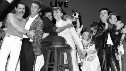 Getty Images A black and white image of David Bowie and other celebrities on stage at Live Aid in 1985.