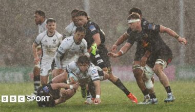 Bernhard Janse van Rensburg powers forward in a rainstorm as various Bristol Bears and Exeter Chiefs players look on.
