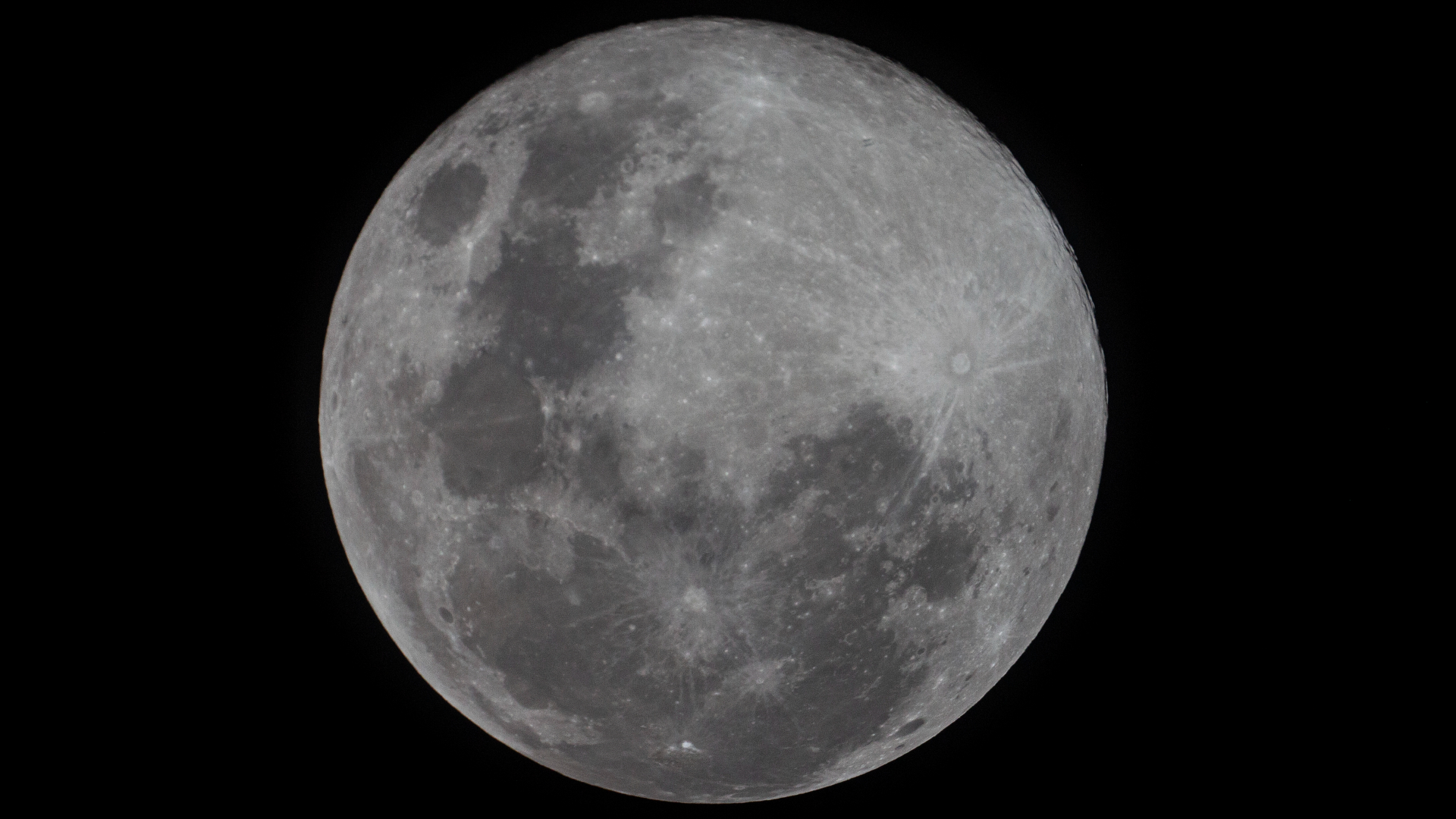 A detailed photo of a full moon shining in a black night sky.