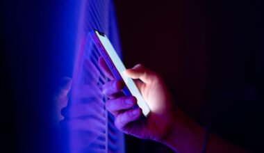 Person holding a smartphone in the dark.