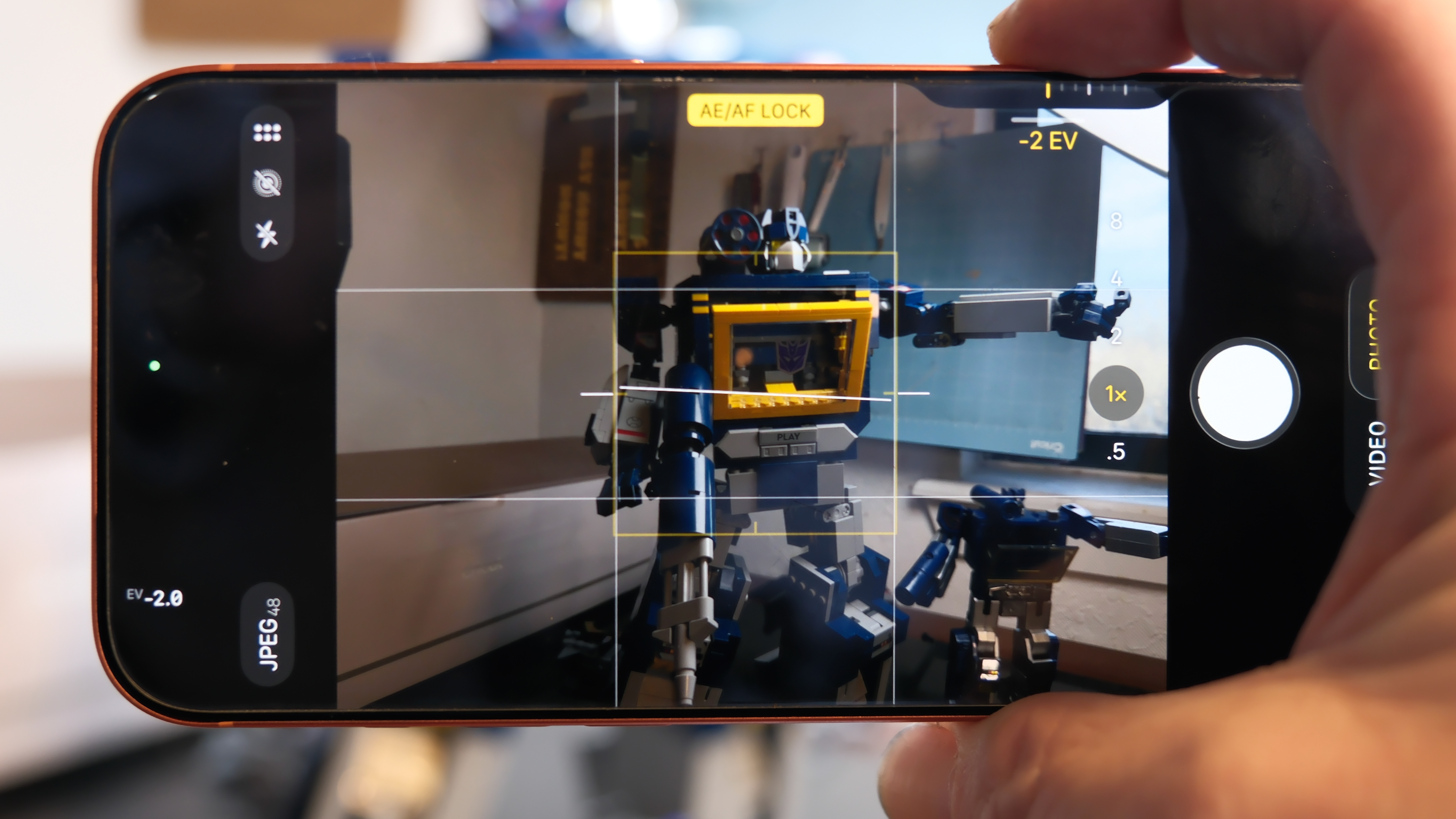 Camera Control button software features on the Apple iPhone 17 Pro Max in Cosmic Orange color, showing zoom, switching cameras, Magnifier app, and more