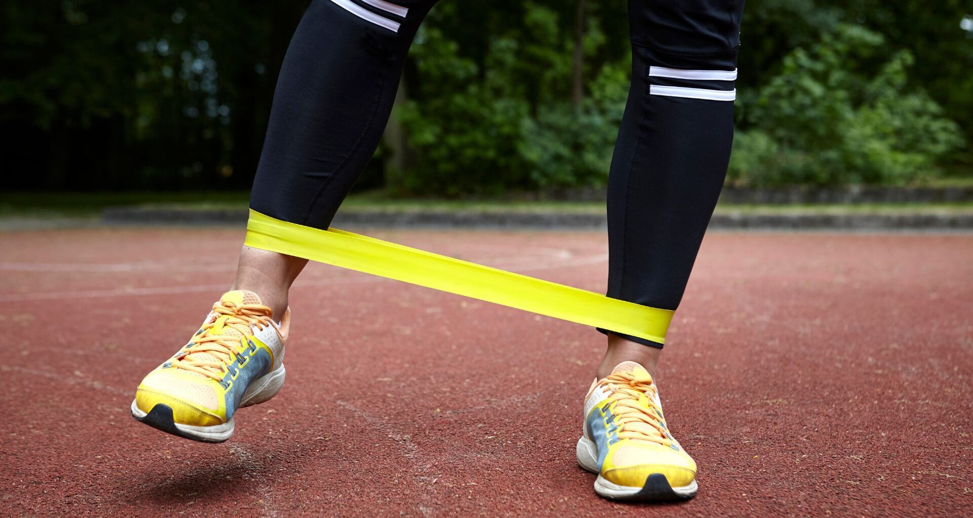 Woman doing crab walk exercise, stepping sideways with resistance band wrapped around trainers