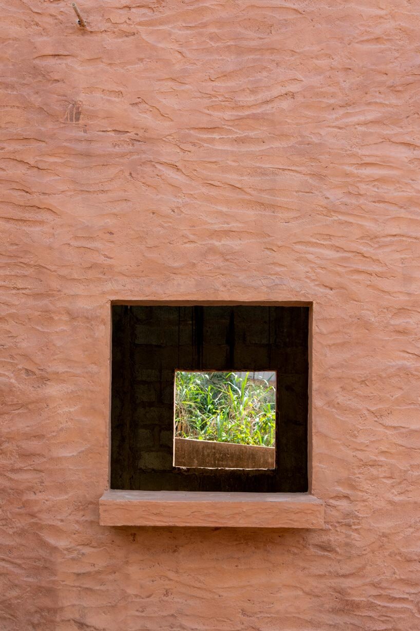 clay-pigmented monolithic villas emerge from ghana’s red earth landscape