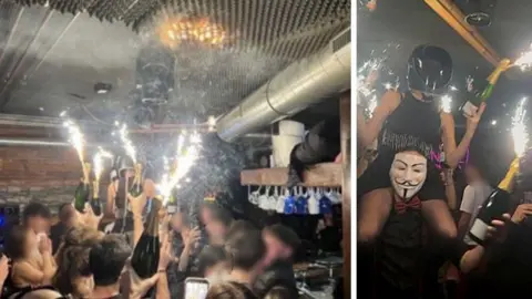 Supplied An image shows a bar full of people holding bottles of champagne with sparklers on the top