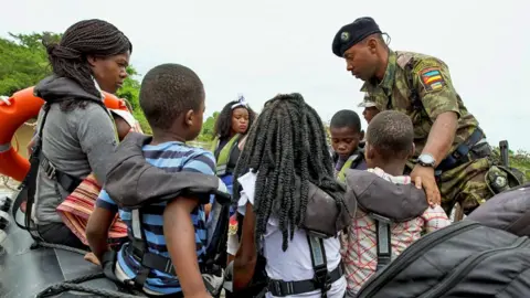 Reuters A soldier helps seat women and children wearing life jackets on a rubber speedboat