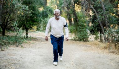 man walking up a bank in a forest, facing the camera wearing a cream sleeved top and navy trousers.