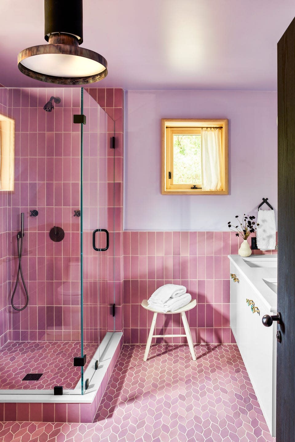 modern bathroom featuring pink tiles and a glass shower