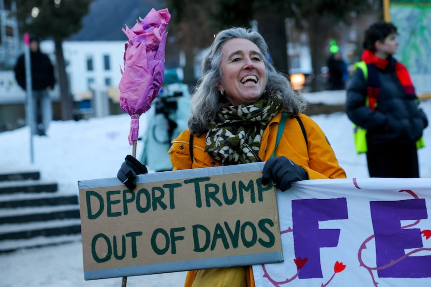 An activist holds a placard saying Deport Trump out of Davos