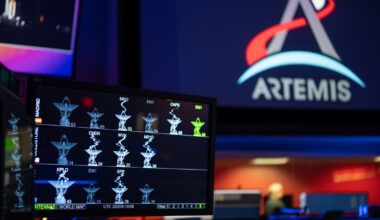 The DSN Now tool is displayed on a screen in the foreground—antenna images show real-time data provided by the Deep Space Network ground stations. The Artemis logo is seen in the background on a large screen.