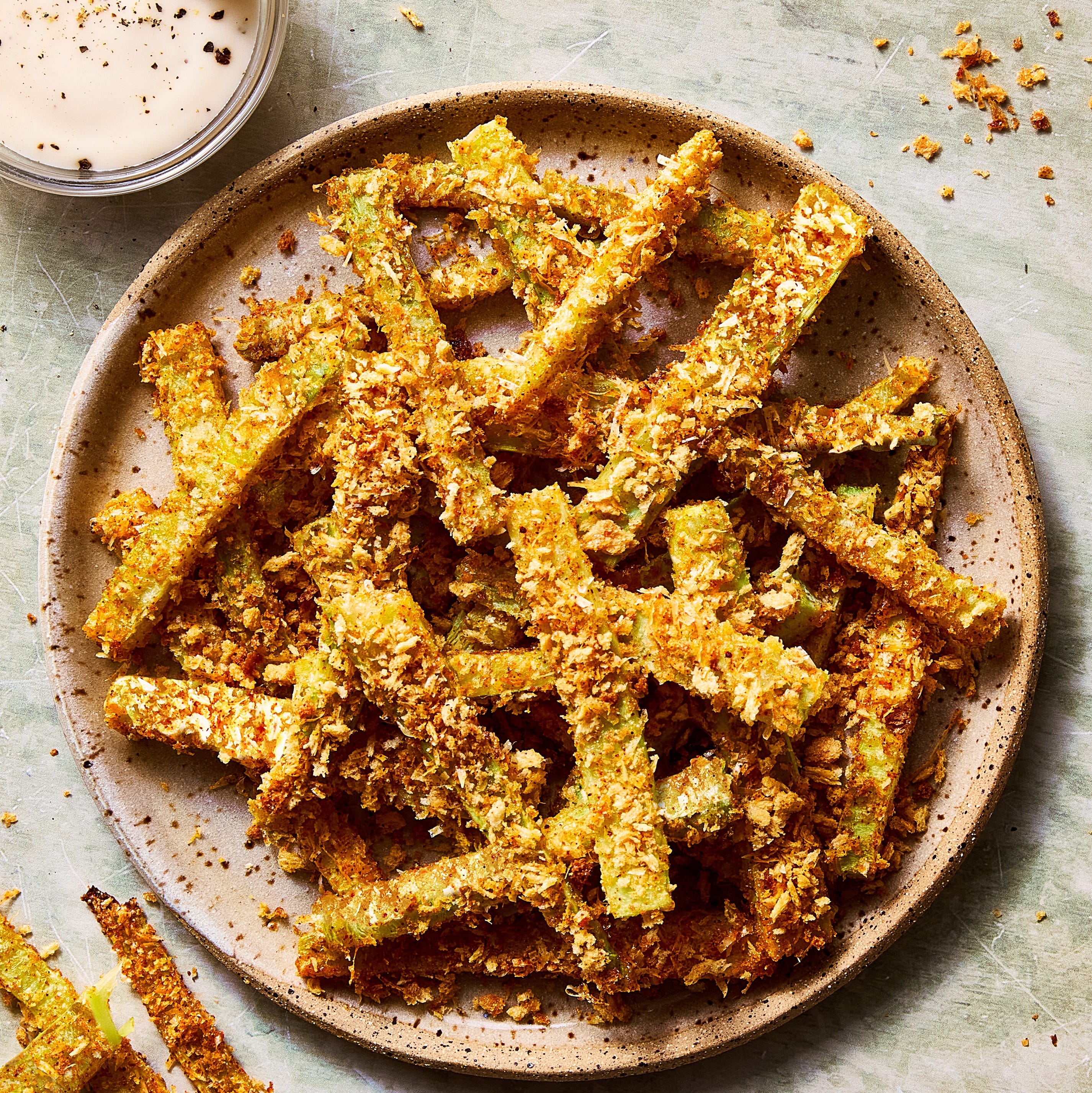 crispy parmesan broccoli stem fries on a plate beside a bowl of ranch dipping sauce