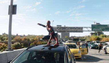 A character named Varang, portrayed by Oona Chaplin, features striking face paint and intricate accessories, set in a dramatic lighting typical of the 20th Century Studios' film 'Avatar: Fire and Ash.' The background includes shadowy figures, highlighting the character's fierce expression.