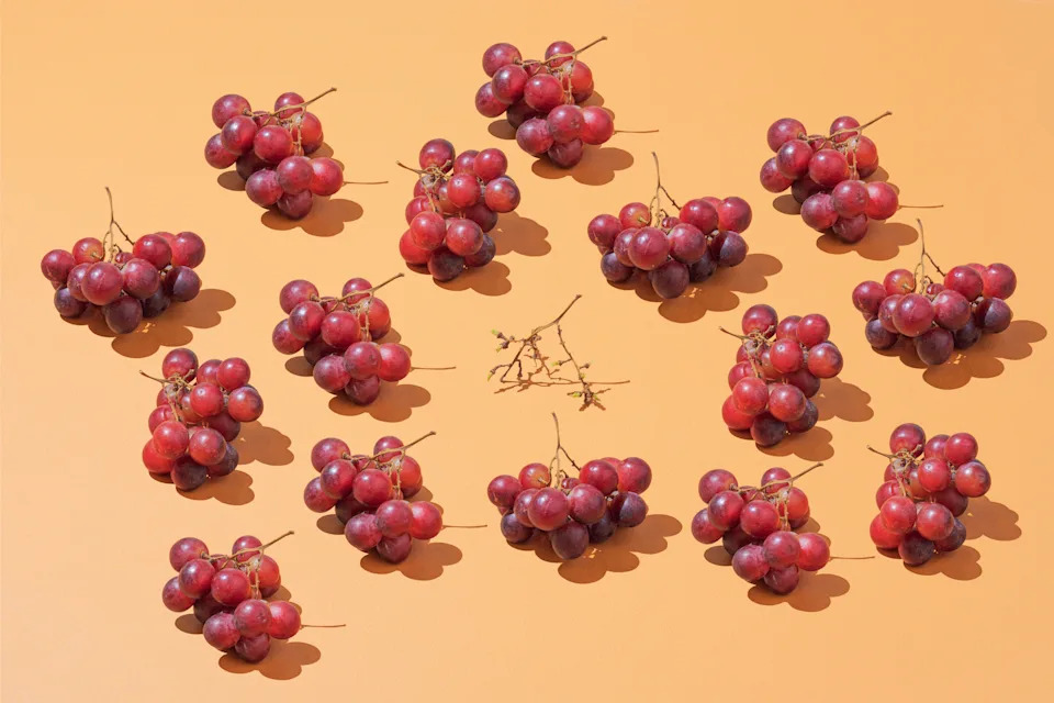 Several clusters of grapes are arranged in a circle pattern on a flat surface, with empty grape stems in the center