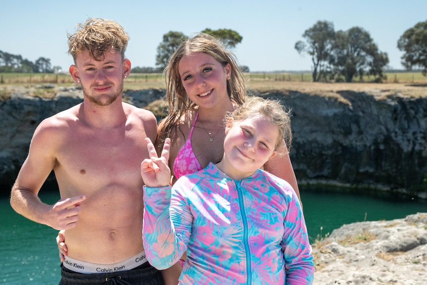 A man, woman and young girl posing for a photo with a swimming lake behind them