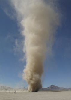 A large cone of dust rising out of a desert.