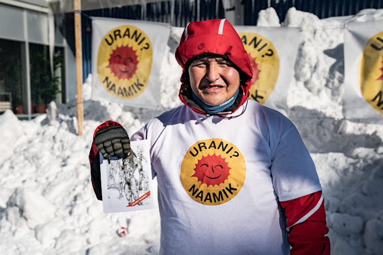 a campaigner holds up an anti-uranium flyer in greenland in the run-up to the 2021 election.