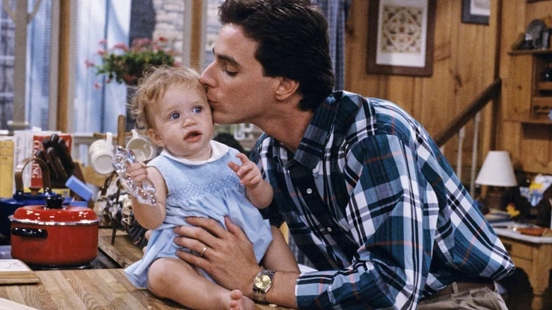 Danny kissing the forehead of baby Michelle