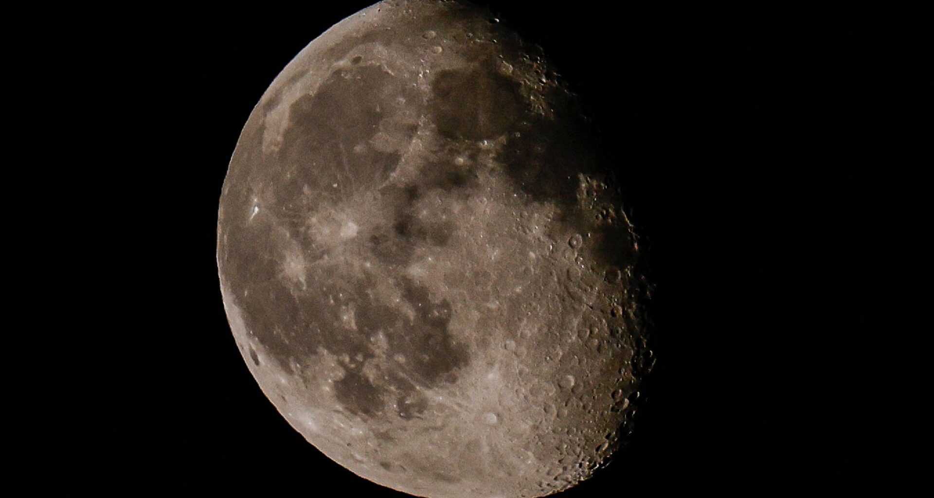 The moon is pictured in a black night sky, with a portion of its right side bathed in shadow.