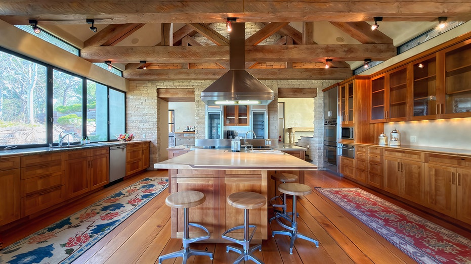 The kitchen features a large center island and exposed wooden beams.