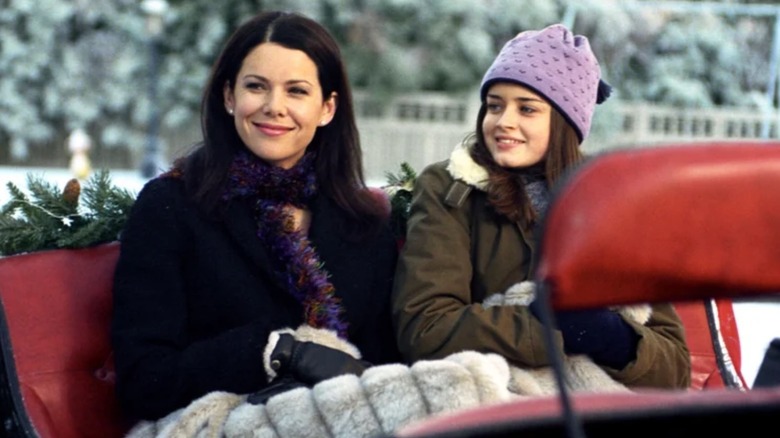 Lorelai Gilmore and Rory Gilmore (Lauren Graham and Alexis Bledel) in a sled smiling in Gilmore Girls