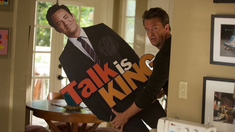 Ryan King (Matthew Perry) holds a cutout of himself in Go On