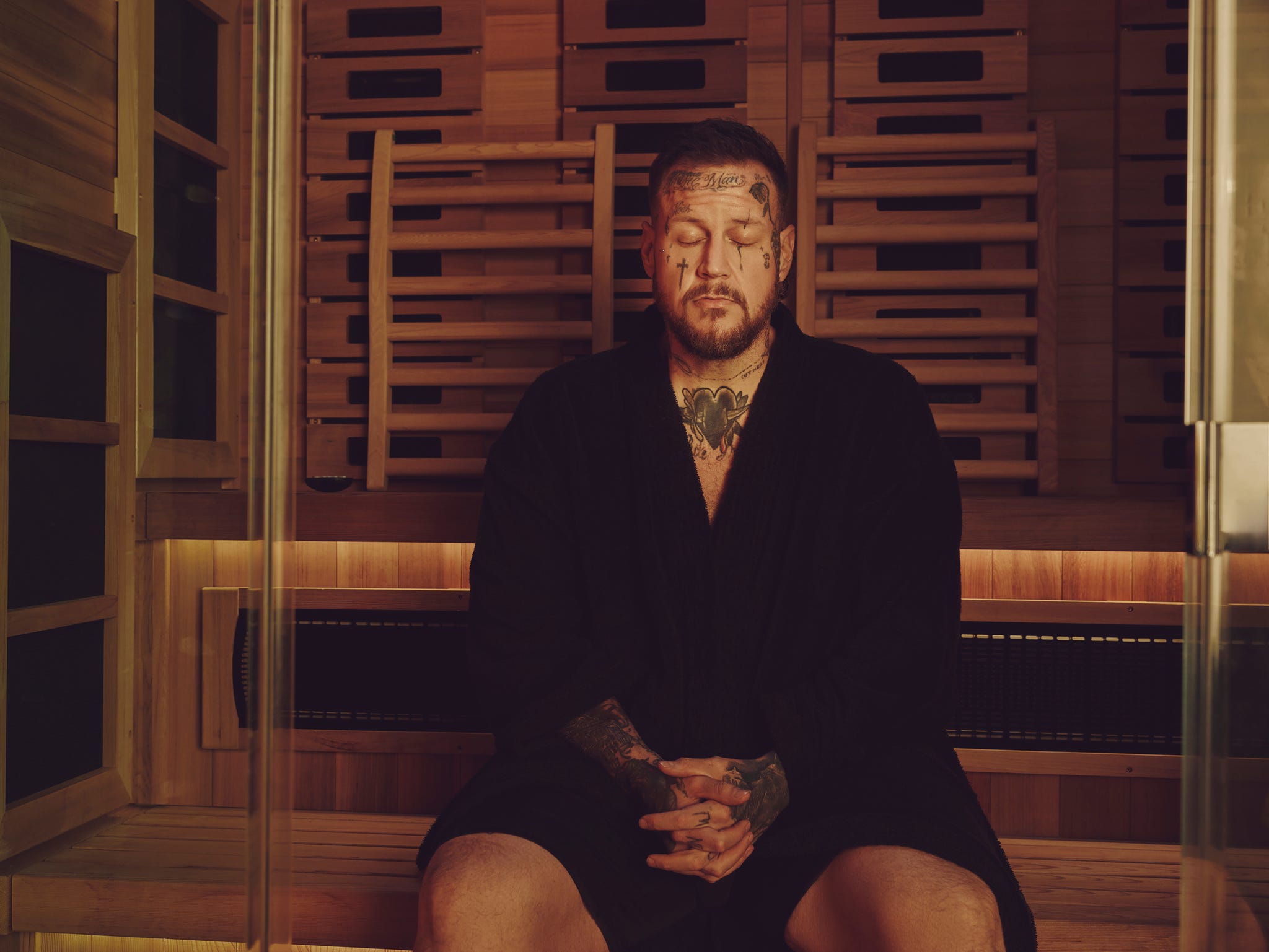 jelly roll sitting meditating inside a sauna.