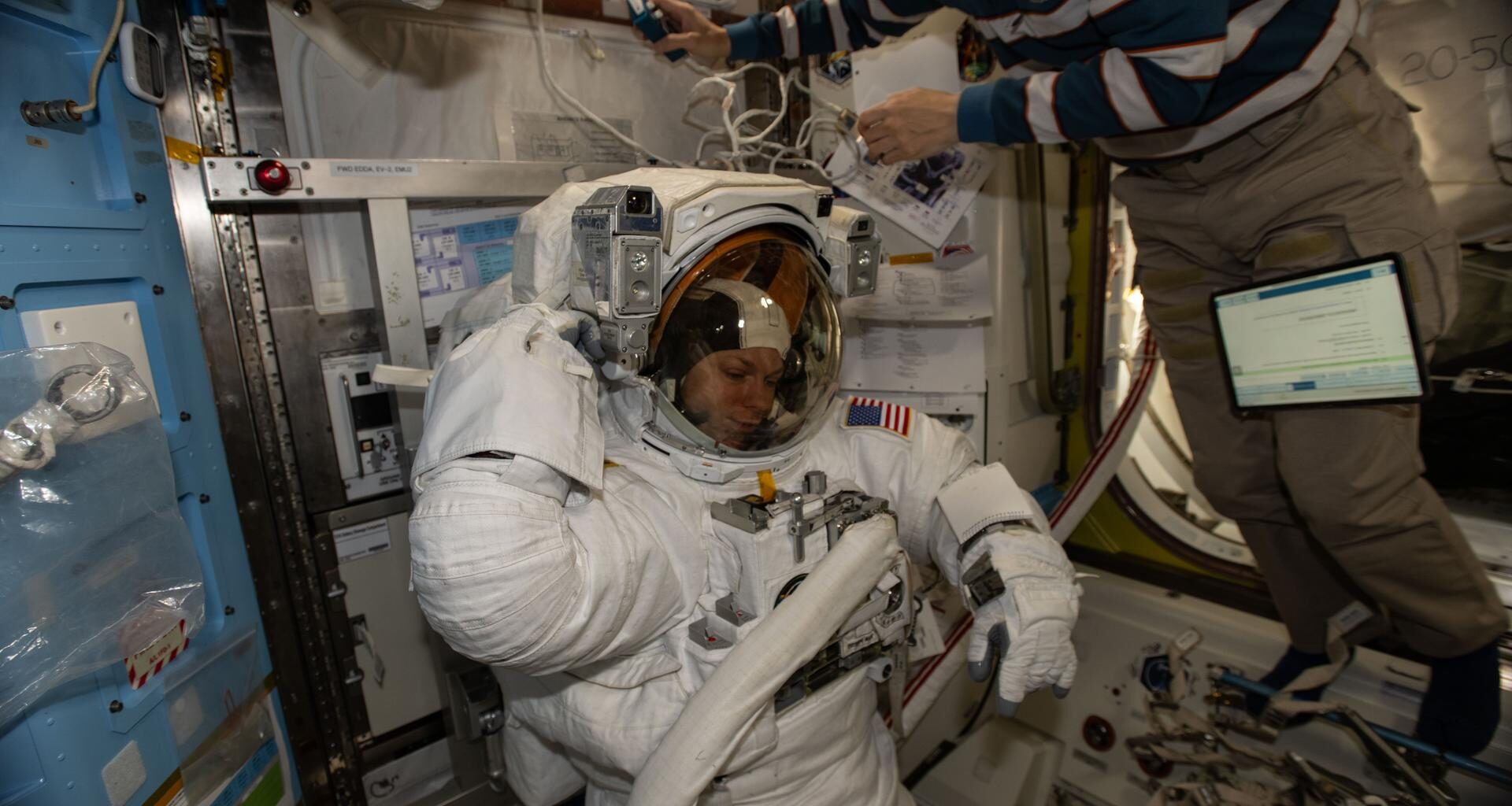 NASA astronaut and Expedition 74 Flight Engineer Zena Cardman is pictured in her pressurized spacesuit, checking its communication and power systems ahead of a spacewalk planned for Thursday, Jan. 8, 2025. At upper right, JAXA (Japan Aerospace Exploration Agency) astronaut and Flight Engineer Kimiya Yui assists Cardman as she tests the operations of her spacesuit inside the International Space Station’s Quest airlock.