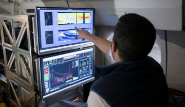 Two computer monitors are shown from the perspective of looking over a researcher's shoulder. The screens show colorful graphs representing smoke and aerosol measurements from previous missions with the HALO lidar instrument.