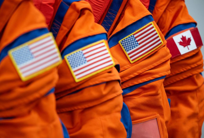 The flags of the United States and Canada are seen on the left shoulder of the Orion Crew Survival System suits on January 17 at Kennedy Space Center.