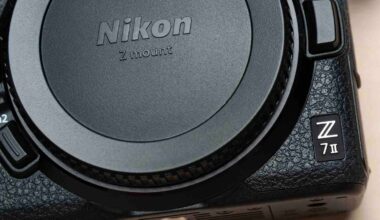 Close-up of a Nikon Z 7II mirrorless camera body, showing the textured grip, control buttons, and prominent Nikon logo on the lens mount cover.