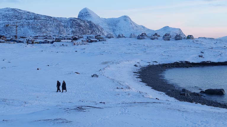 People walk on a beach in Nuuk, Greenland.