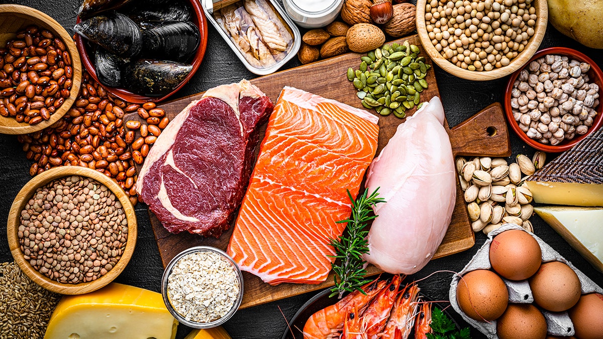 Protein-rich foods like fish, meat, beans and eggs laid out uncooked on a table.