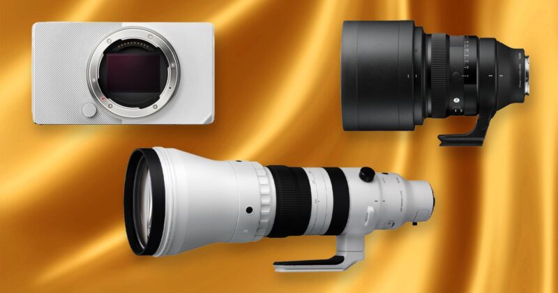 Digital camera body, a large black camera lens, and a long white telephoto camera lens displayed on a gold satin background.