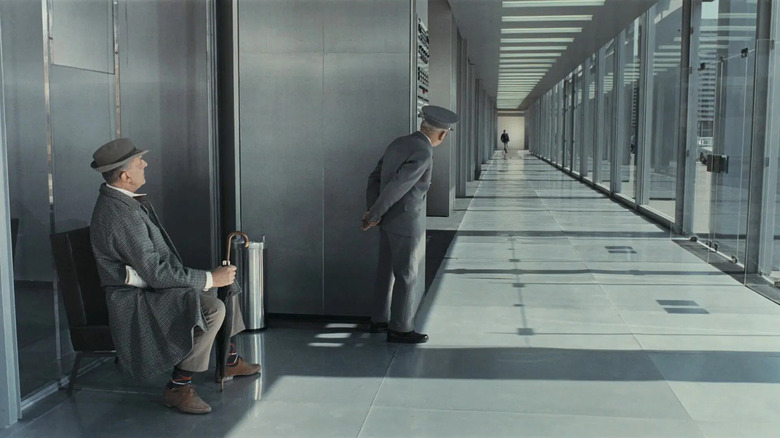 M. Hulot sitting down at the end of a long corridor in Playtime