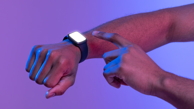 A person lighting up their smartwatch screen on their arm