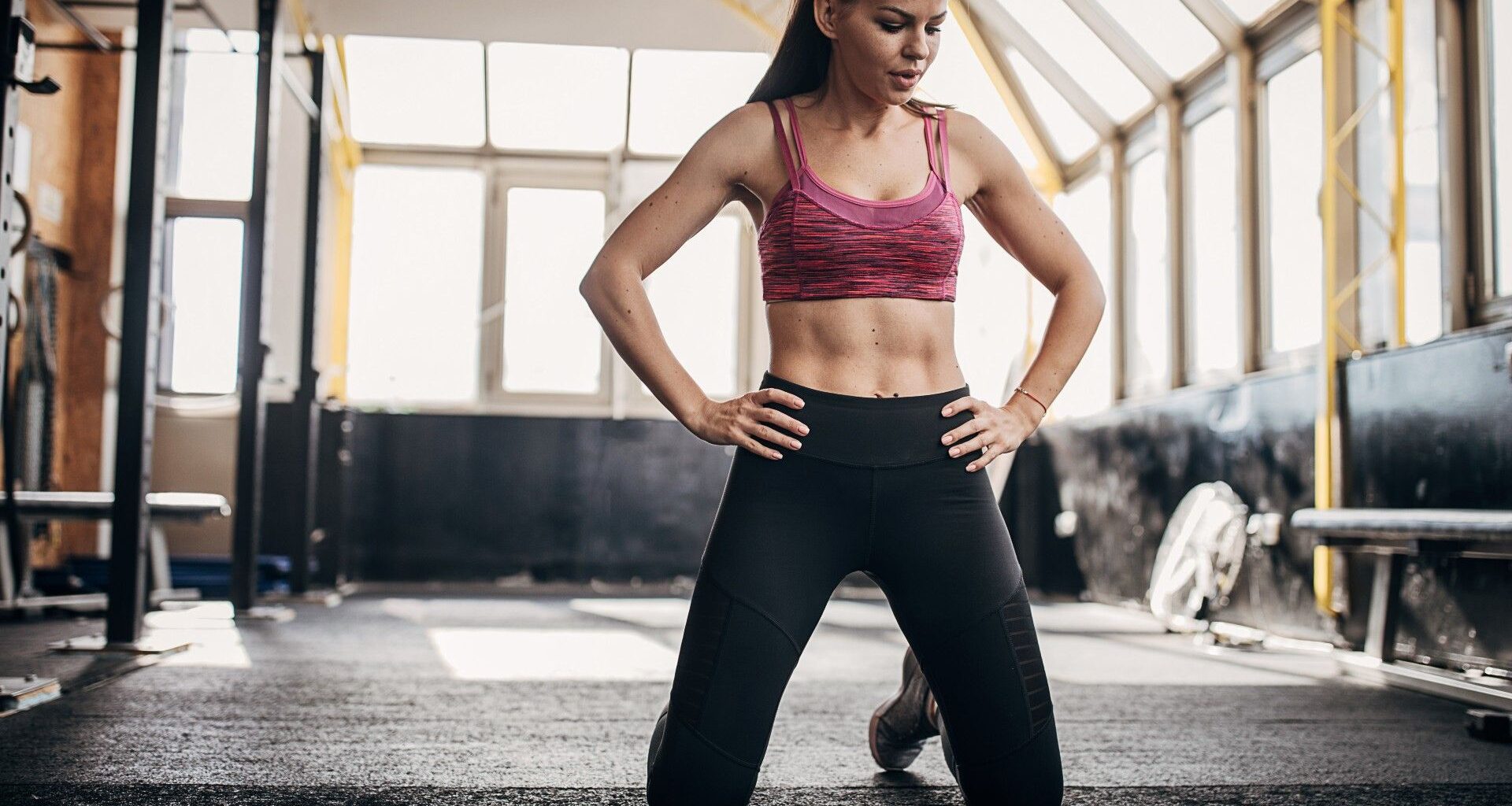 Woman kneeling with hands on hips at the gym studio in activewear