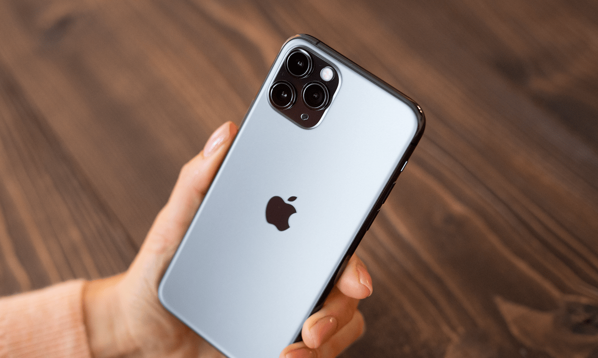 Person holding an iPhone with the Apple logo visible at the back.