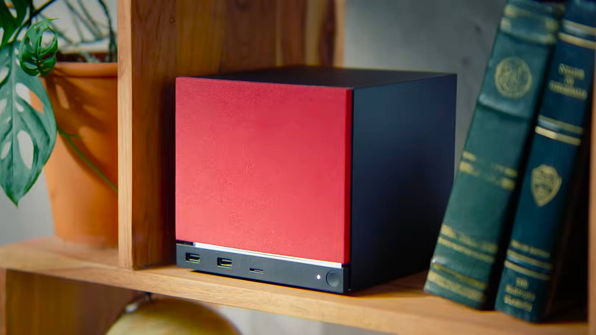 Steam Machine on shelf next to books and plant with red face plate.