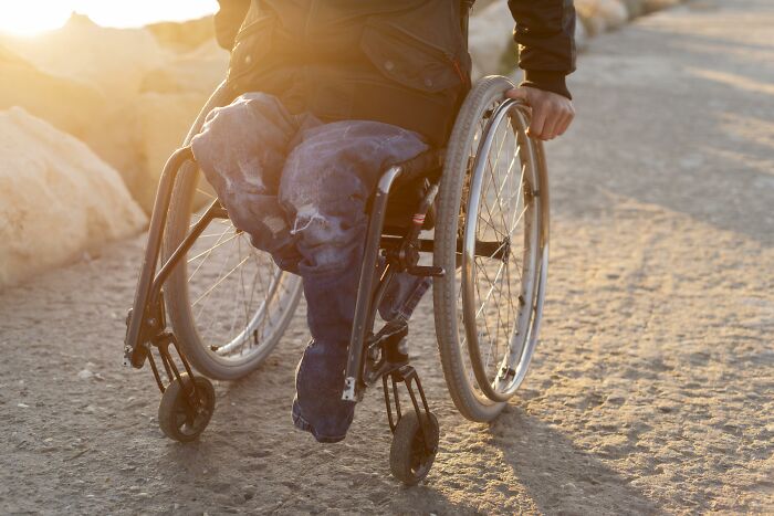 Person in a wheelchair outdoors at sunset, representing patients leaving the hospital against medical advice scenarios.