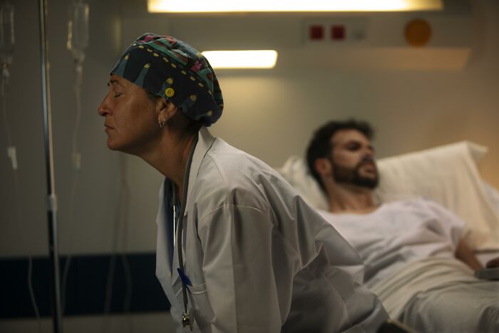 Medical professional leaning forward near a patient in hospital bed, illustrating patients leaving against medical advice.