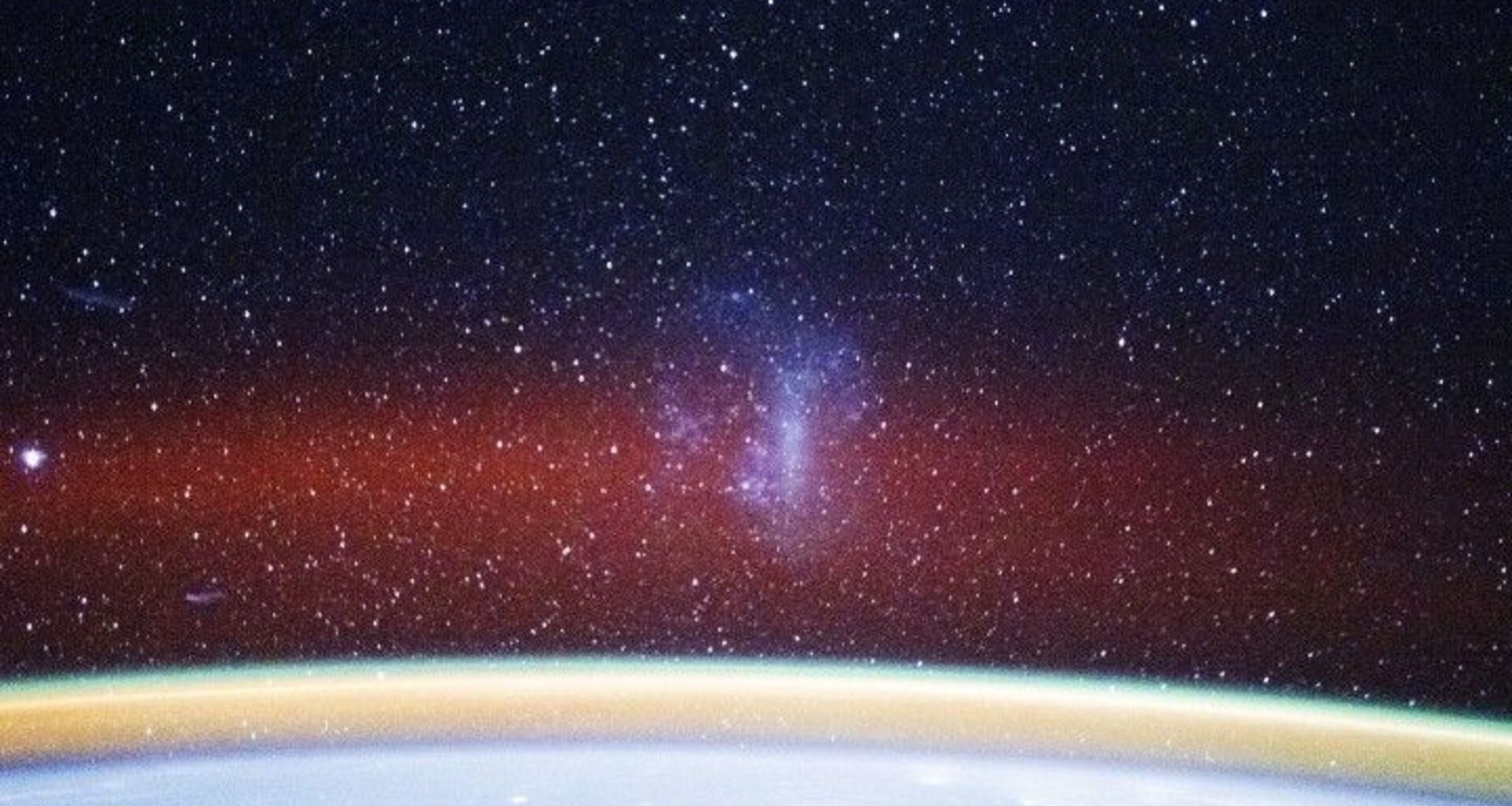 A curved white arc at the bottom of the image glows with a gold band and red fuzzy band of light above it with stars in the distance and a smoky purple shape in the center of the image