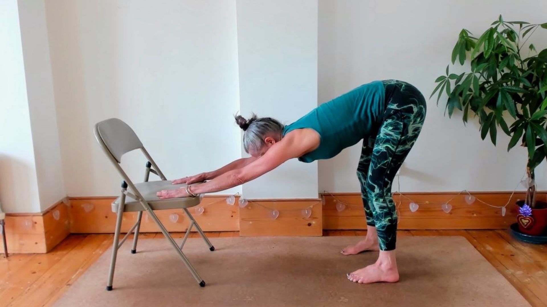 Dina Cohen demonstrates the downward dog pose in chair yoga