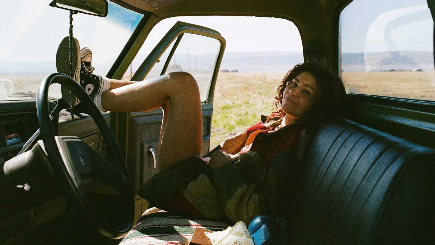 Zendaya as Rue Bennett sitting in a car with her feet on the dashboard in Euphoria