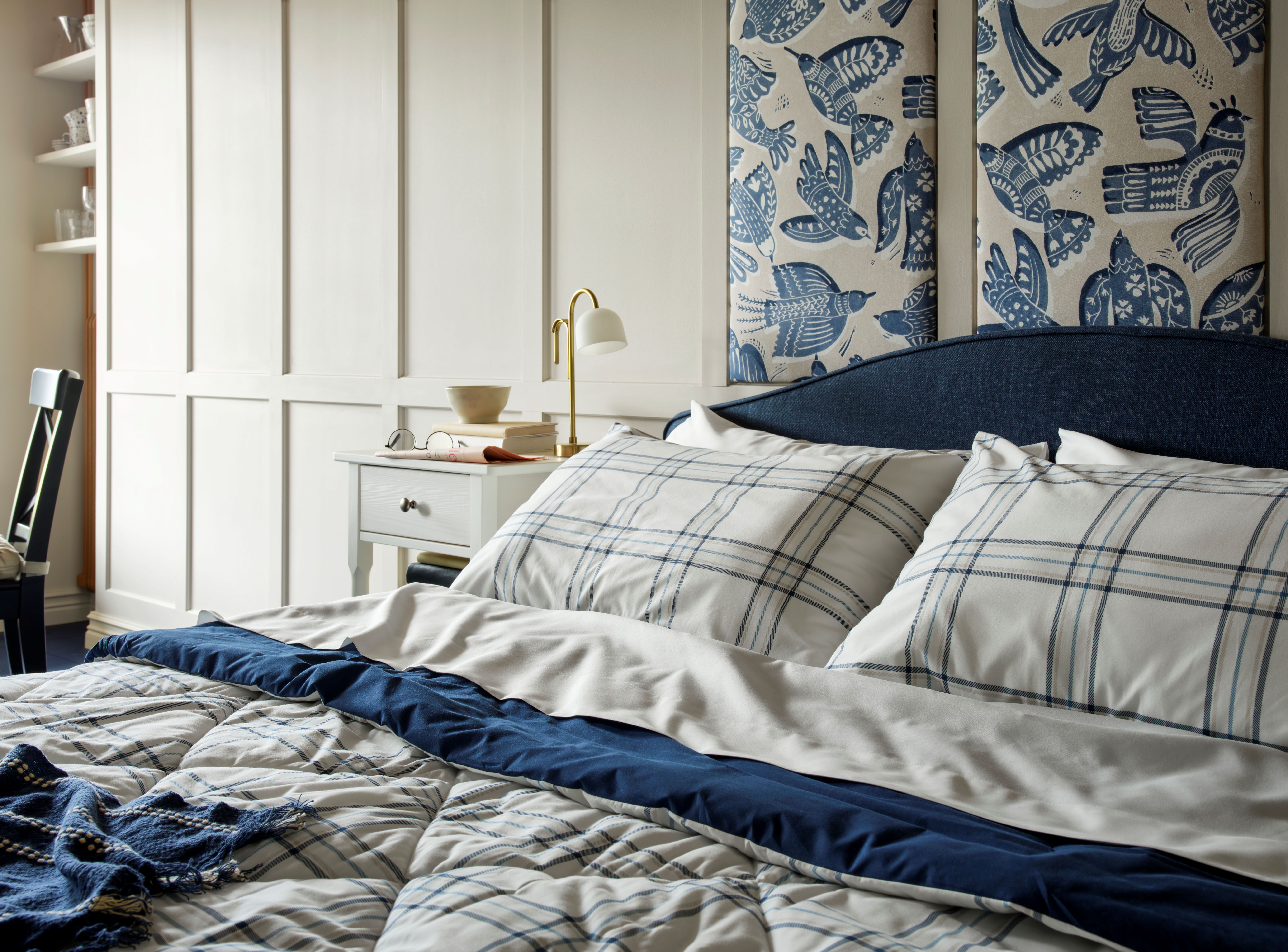 A blue and white themed bedroom with plaid bedding and bird-patterned wall hangings.