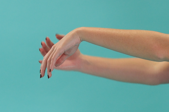 Two arms and hands performing a wrist extensor stretch.