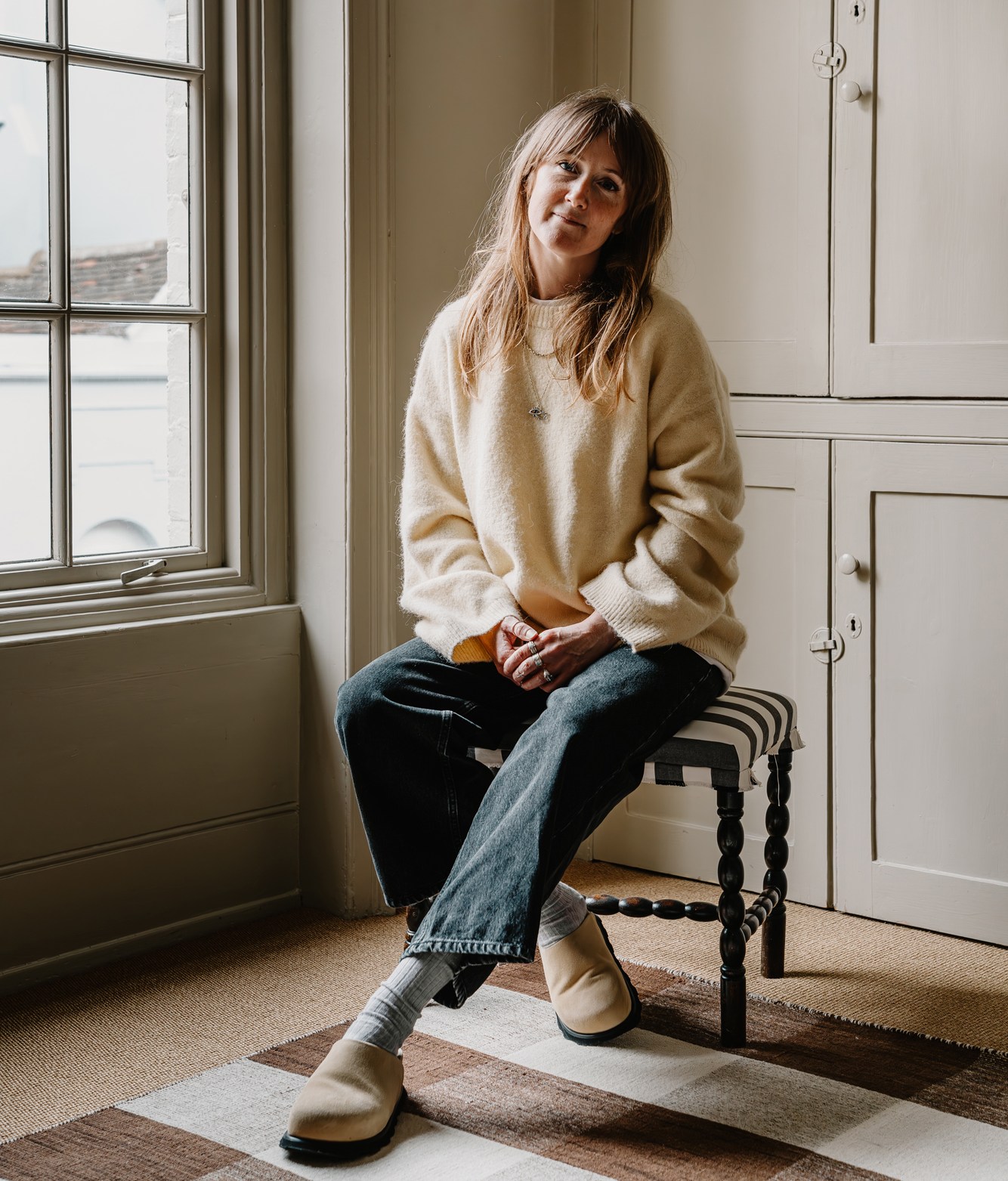 Sarah Pinn of Cote de Folk sitting on a stool in a room.