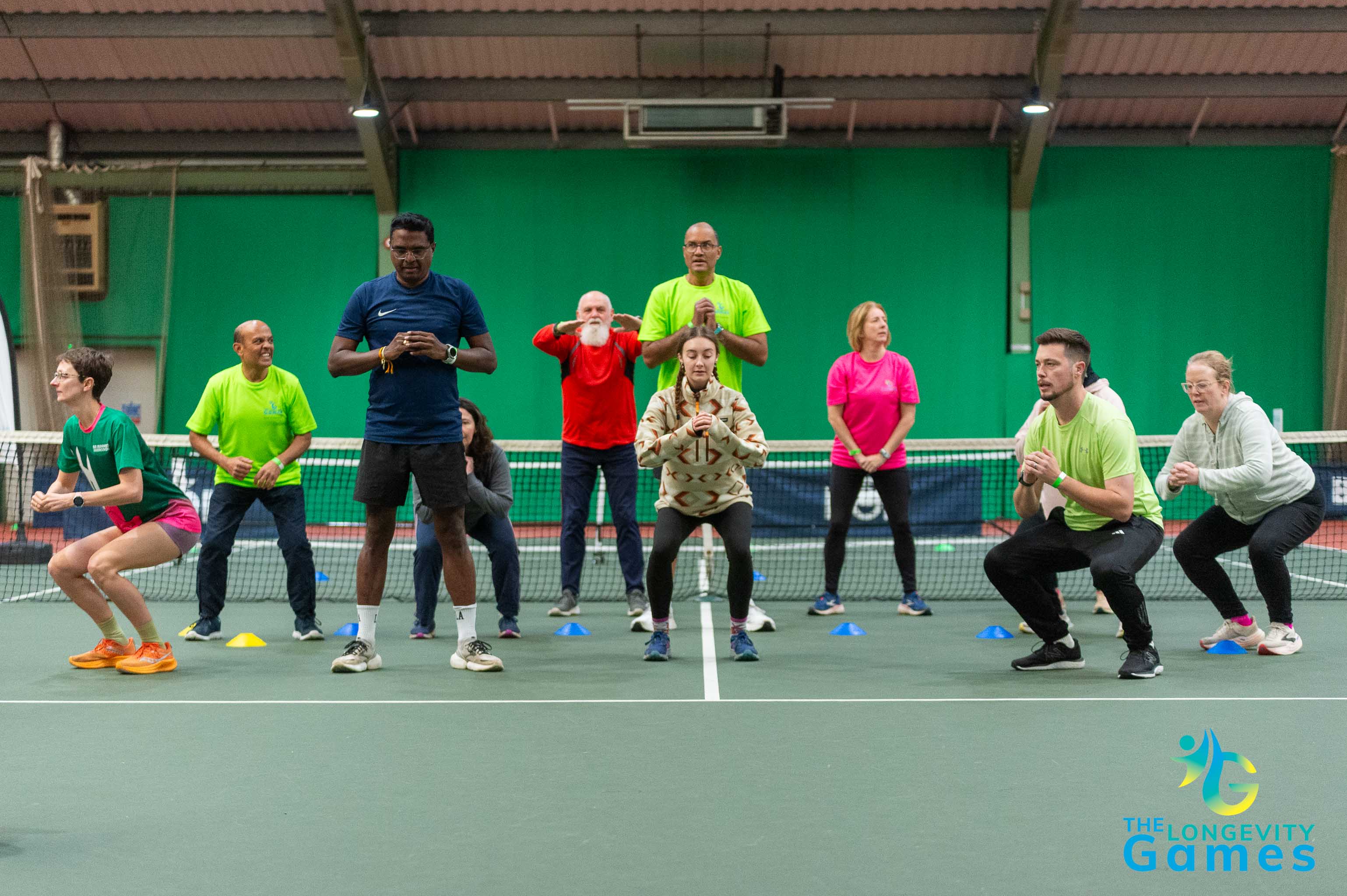 Competitors at The Longevity Games doing squats on a tennis court.