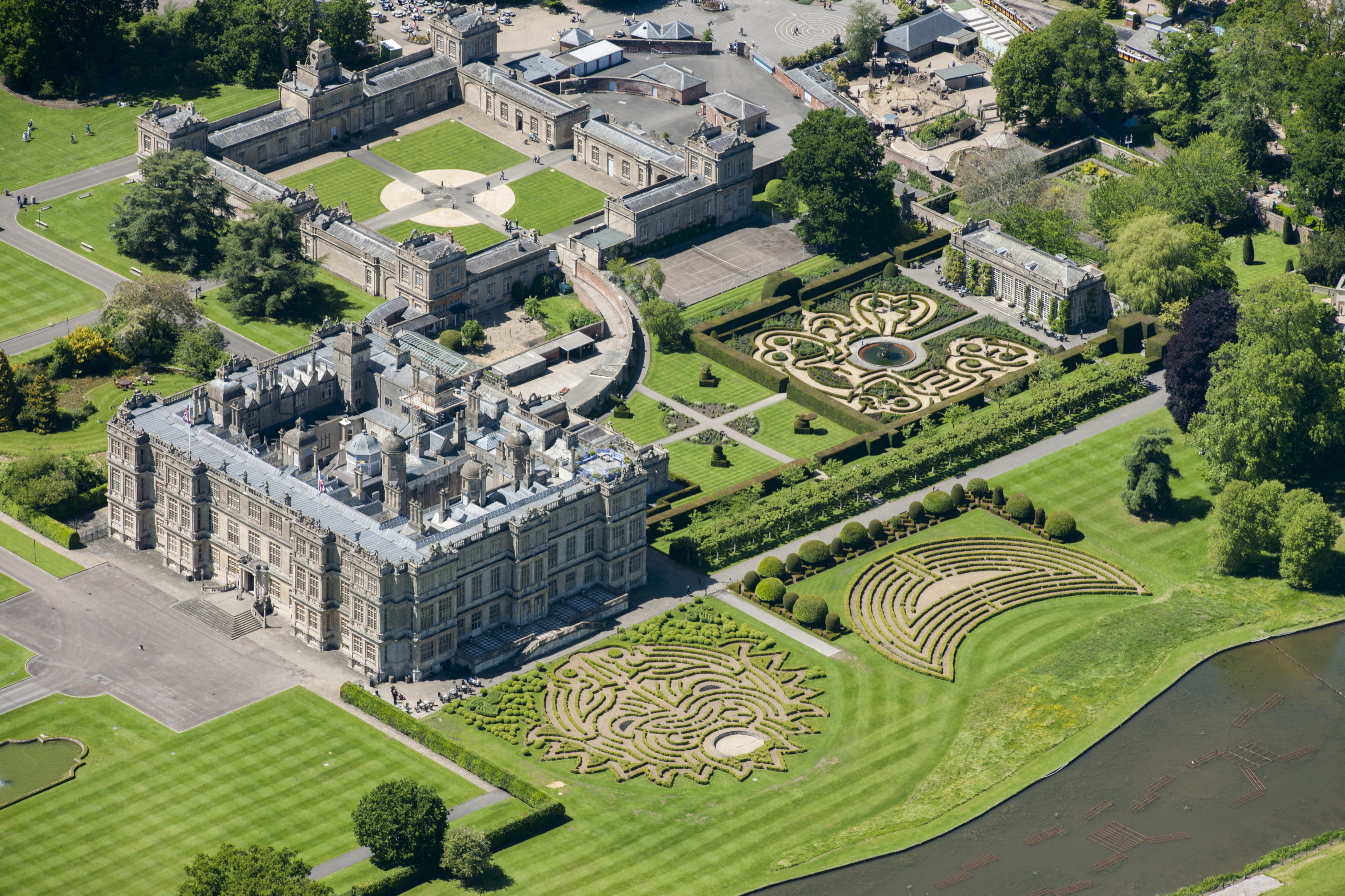 Aerial view of Longleat, an Elizabethan stately home, and its extensive gardens, including a maze and shaped hedges.