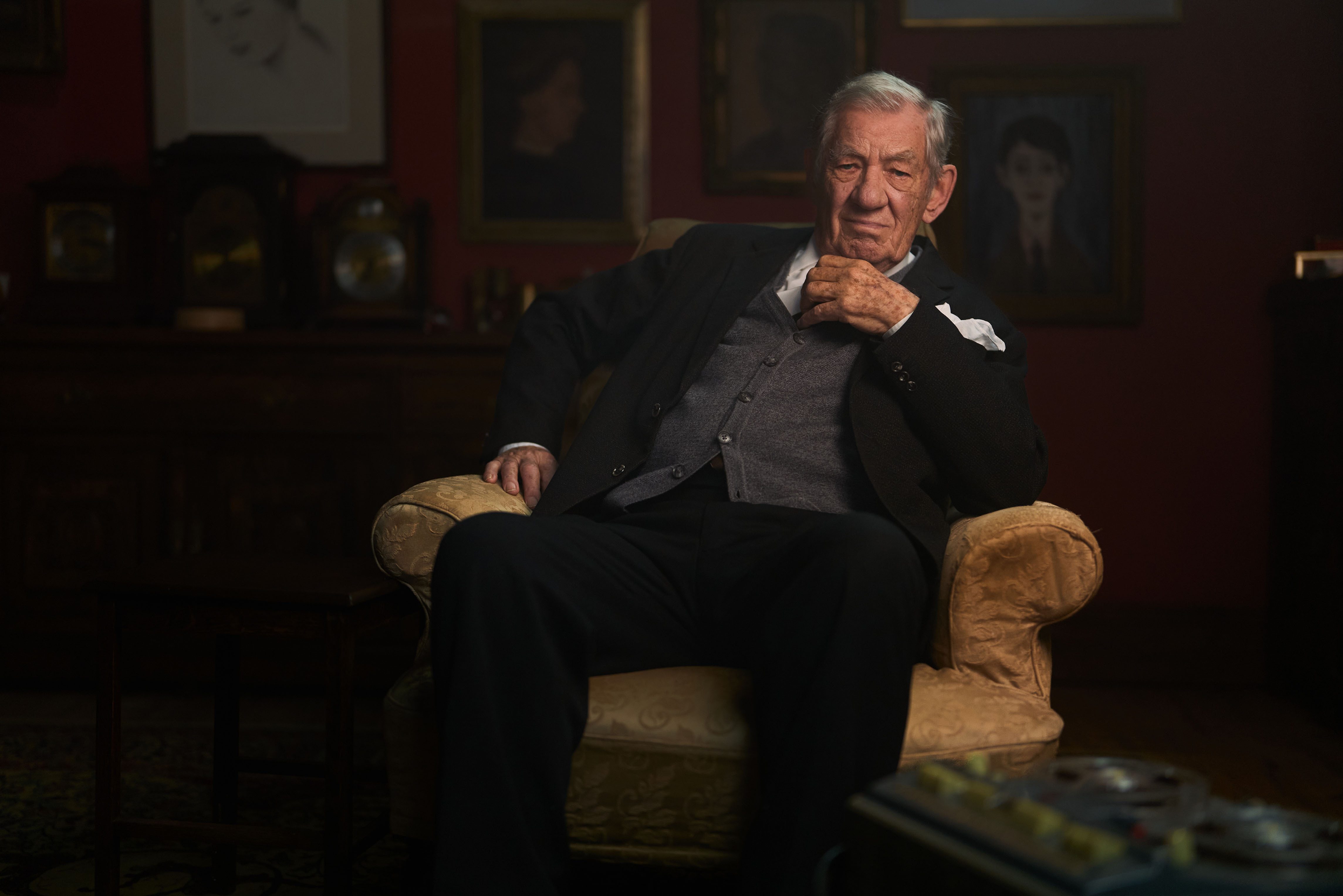 Ian McKellen as L.S. Lowry sitting in an armchair, with a tape recorder visible in the foreground.